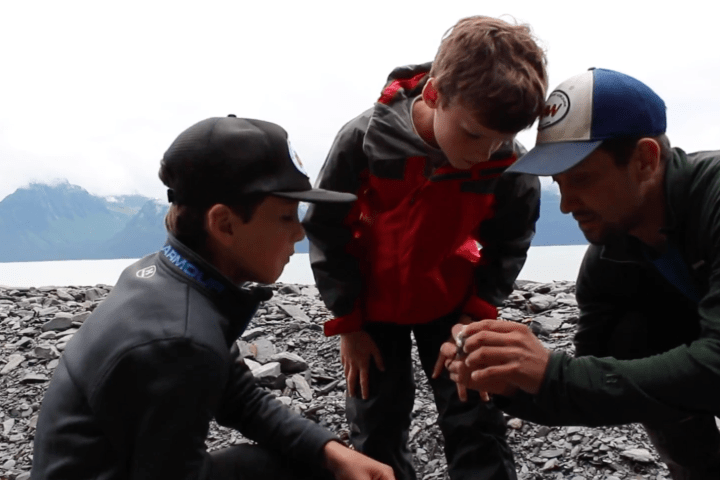 Kayak guide teaching kids about intertidal life at Tonsina Point on a guided private family sea kayak tour